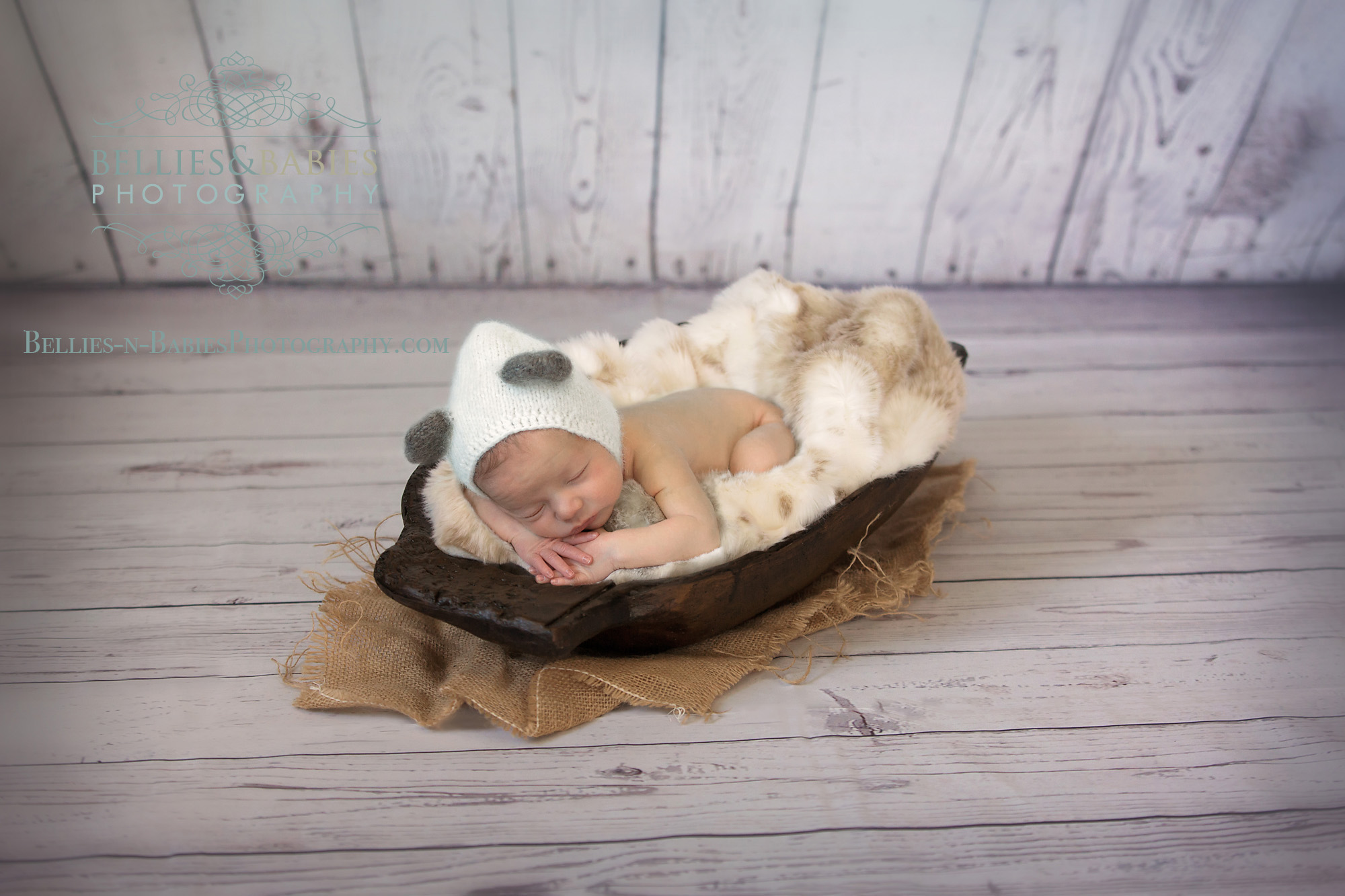 newborn in trencher bowl, fur, wood wall